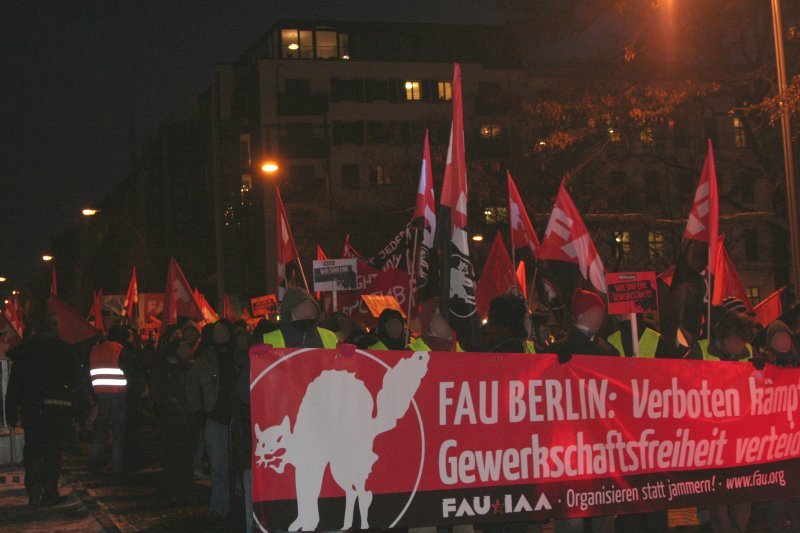 Manifestation vue de face, de la FAU. La banderole semble en allemand: logo d'un chat blanc sur une banderole noir et rouge [anarchiste donc]